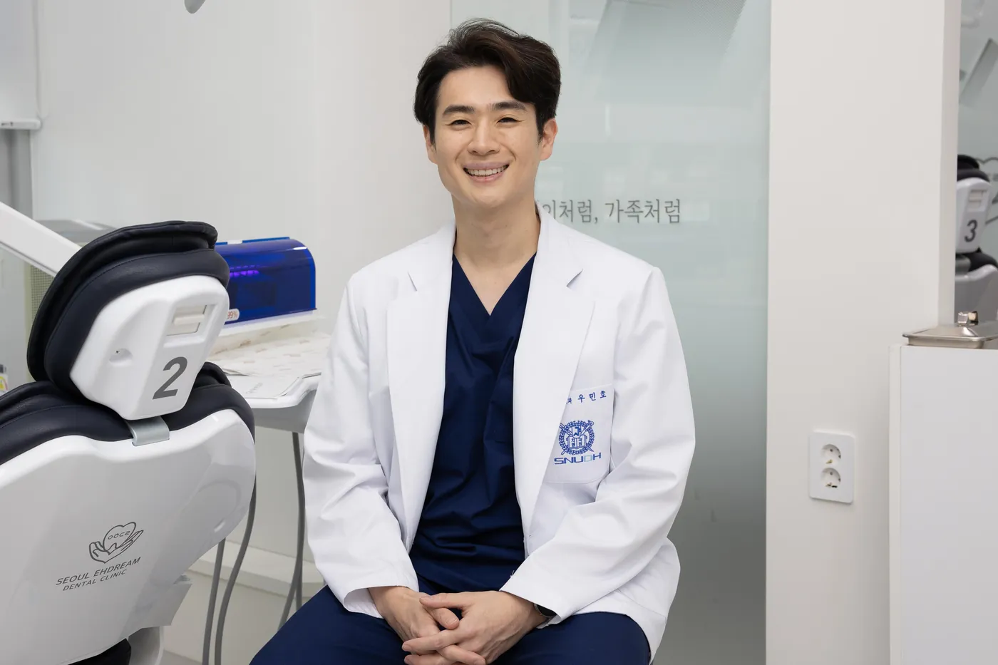 진료 의자 옆에 앉아 있는 우민호 대표원장