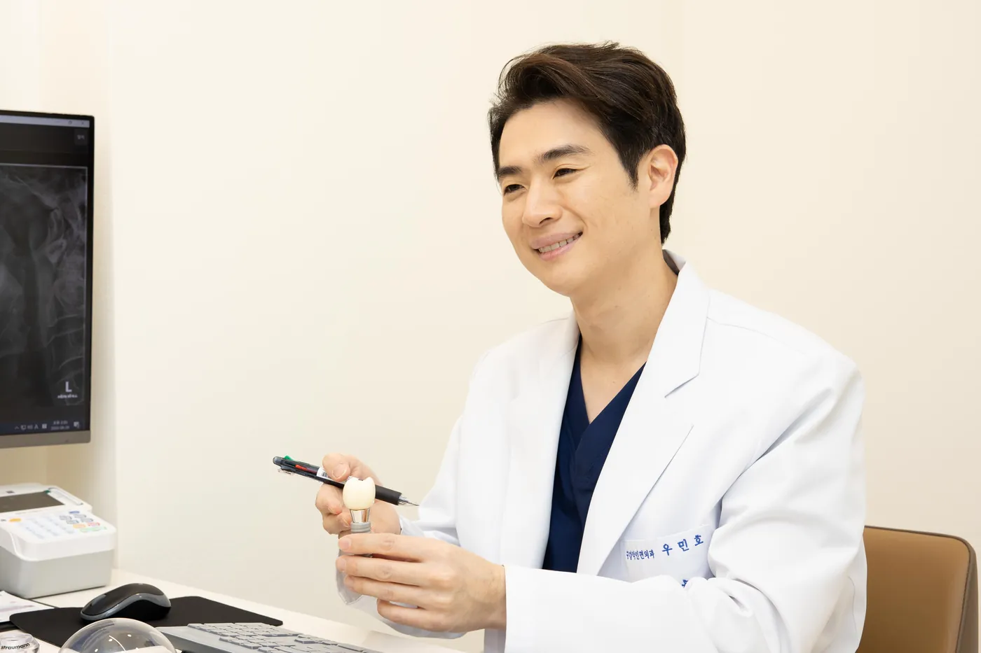 임플란트 모형을 들고 설명하는 우민호 대표원장
