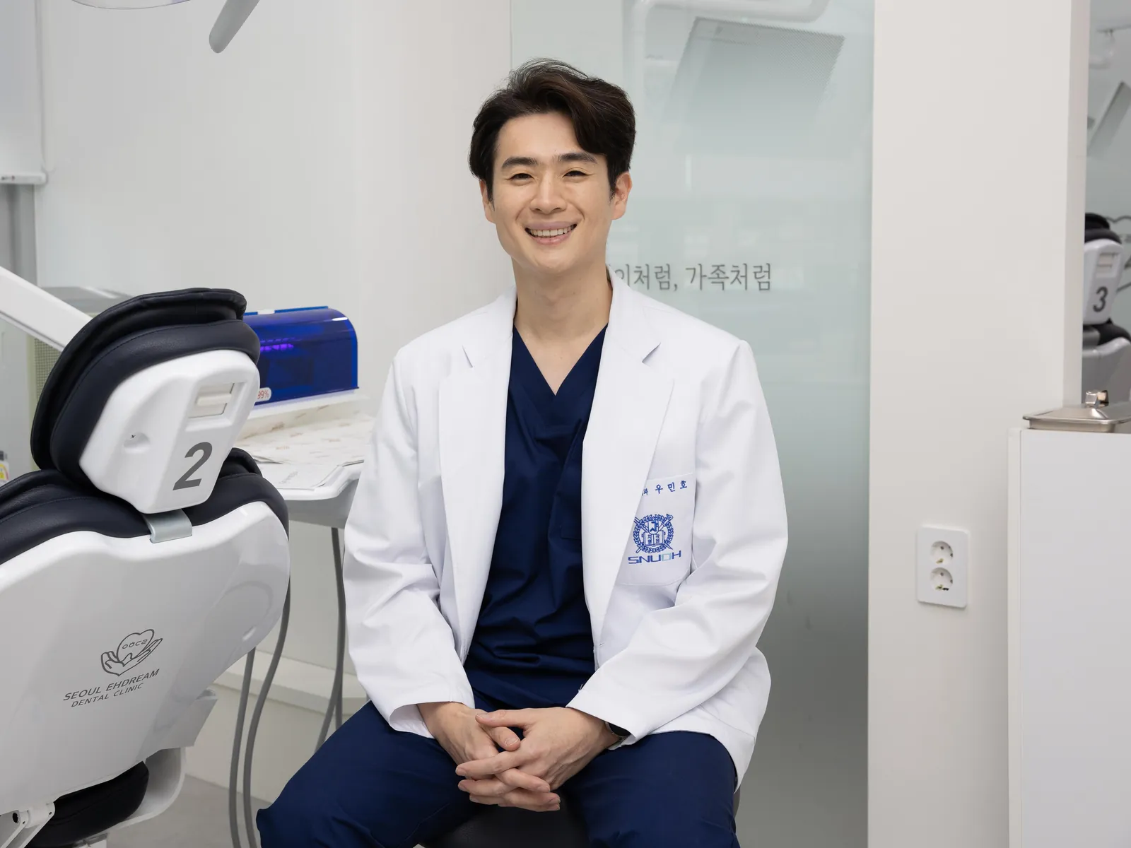 진료 의자 옆에 앉아 있는 우민호 대표원장